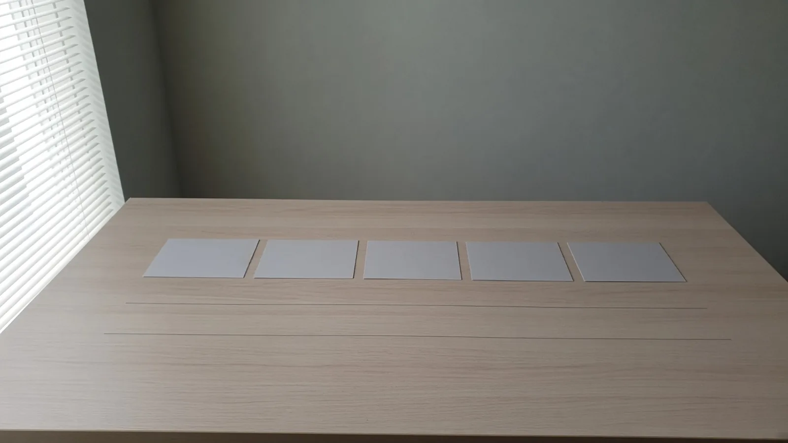 Five blank cards in a row on a wood table, with two empty rules beneath them.